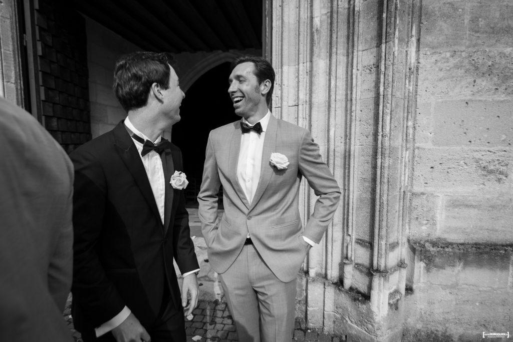 éclats de rires entre le marié et son témoin à la sortie de l'église